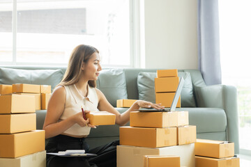 Wall Mural - Small business startup, SME owner, female entrepreneur working on receipt boxes and checking online orders, laptop to prepare to pack boxes to sell to customers. Close-up photo