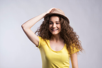 Poster - Portrait of a gorgeous teenage girl with curly hair and hat. Studio shot, white background with copy space