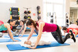 © Halfpoint - Mother smiling at baby while performing push-ups. Group exercise class, fitness or pilates for parents. Moms staying active while boding with babies.