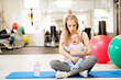 © Halfpoint - Portrait of new mom holding crying baby during group exercise class in gym. Moms staying active while boding with babies.
