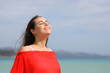 Happy woman in red breathing fresh air on the beach