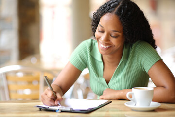 Happy black woman filling form in a terrace