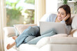 Full body portrait of a happy woman using laptop at home