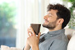 Happy man smelling coffee  siting on a couch