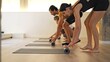 © luisrojasstock - Group of four rolling up yoga mats in a modern studio setting.