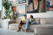 Joyful loving creative couple artists have casual conversation sitting on couch with laptop smiling looks on screen discuss share ideas for art. Relaxed man and woman enjoy rest time together at home.