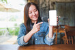 © Farknot Architect - Mockup image of a young woman holding, showing and pointing finger at a mobile phone with blank white screen