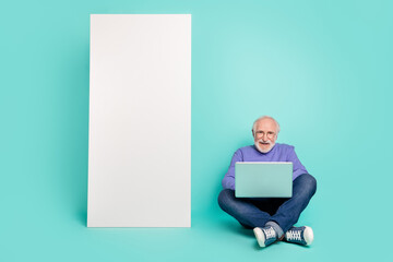 Poster - Full length photo of cheerful aged man sit floor use netbook huge empty space telephone isolated on cyan color background