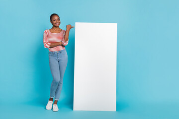 Full body portrait of cheerful lady direct thumb finger empty space ui panel screen isolated on blue color background