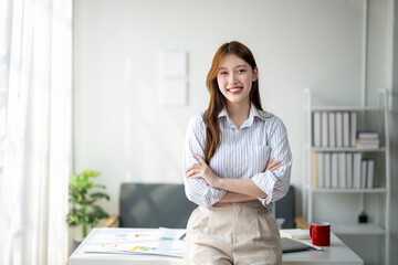 Wall Mural - A woman is posing for a picture in a room with a couch and a potted plant. She is wearing a white shirt and tan pants and is smiling