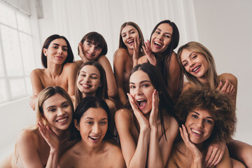 Wall Mural - Group photo of ten girlfriends in beige bras laughing together touch imperfections at studio white color background