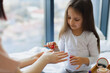 © sofiko14 - Cute little girl learns to paint her nails by applying polish on mother hands. Happy mother and daughter sitting in bed at home and doing manicure, taking care of their body.
