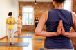 © Dasha Petrenko - Close-up of a woman practicing yoga at a fitness club. Hands in the namaste gesture. A group of young women for a yoga class in the Paschim Namaskarasan pose.