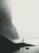 Lonely figure stands on rocky shore of misty fjord