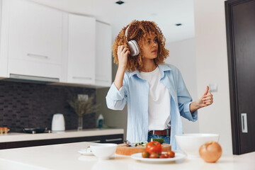 Wall Mural - Woman standing in kitchen with cup of coffee and plate of food in hand, ready for a morning meal