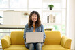 Portrait of attractive young Asian female graphic designer looking at the camera while working with laptop computer sitting on office cozy sofa.