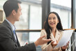 © wichayada - A young businessman and a female Asian accountant are discussing financial accounting and business planning together in the office.