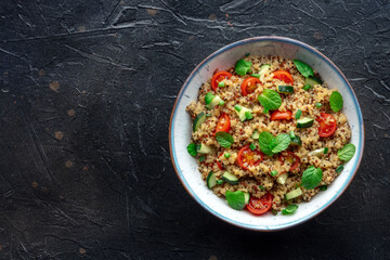 Wall Mural - Quinoa tabbouleh salad in a bowl, a healthy dinner with tomatoes and mint, shot from above with a place for text