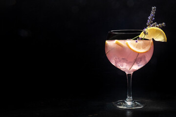 Poster - Fancy cocktail with fresh fruit. Gin and tonic drink with ice at a party, on a black background. Alcohol with lavender and lemon, with a place for text