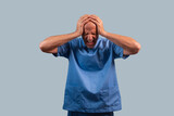 Fototapeta  - Portrait of a physiotherapist in light blue gown and hands on head.