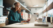 © Gorodenkoff - Dedicated Caucasian Female Student Engaged in Online Learning at a Modern Library. Young Woman Wearing Headphones, Using Laptop to Study, Surrounded by Books and Academic Atmosphere.