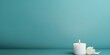 Cyan background with white thin wax candle with a small lit flame for funeral grief death dead sad emotion with copy space texture for display 