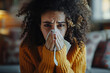 African American woman is seen covering her mouth with a napkin, likely due to a runny nose or cough. She appears to be taking necessary precautions to prevent the spread of germs. Flu, virus concept