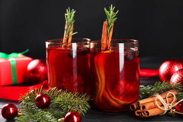 Wall Mural - Aromatic Sangria drink in glasses, ingredients and Christmas decor on black wooden table