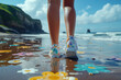 Lower legs in star-patterned sneakers on a sandy beach, with sea droplets on skin, against a backdrop of cliffs and sky.