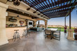 © Wirestock - an outdoor kitchen with a large bar and two tables on the porch
