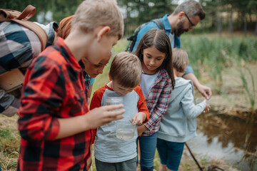 Poster - Young students analyzing water quality, ph level with indicator strips during biology field teaching class. Female teacher during outdoor active education.