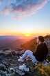 Young woman sitting on the edge of Reed Lookout cliff and enjoying sunset in Grampians mountains, Victoria, Australia