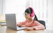 Portrait of Asian girl using computer to learn lessons in elementary school. Student nerd glasses girl study in primary. Children gadgets in classroom. Education knowledge, technology internet network