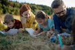 © Halfpoint - Young students learning about nature, forest ecosystem during biology field teaching class, writing notes. Teachers talking with children during outdoor active education.