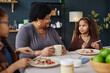 Portrait of senior Black woman with two children enjoying breakfast together at kitchen table
