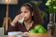 Portrait of teen African American girl drinking milk sitting at dining table during breakfast