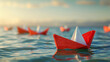 © Natalia - Red and white paper boats floating on blue water with a soft golden sunset in the background.