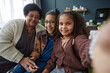 Portrait of happy African American grandmother taking selfie photo with two girls at home