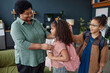 Waist up portrait of smiling African American grandma helping two young girls getting ready for school