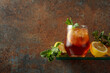Iced tea with lemon and mint on a background of rustic wall.