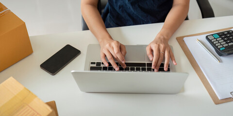 Woman in an online store check the customer address and package information on the laptop. Online shopping concept