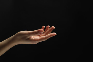 Wall Mural - woman holding something in hand on black background, closeup. space for text