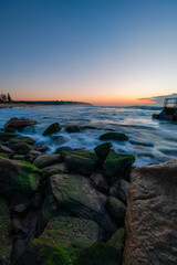 Wall Mural - Sunrise seascape at a rocky coastline.