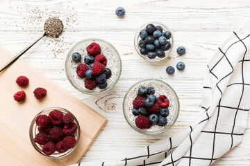 Wall Mural - Healthy breakfast or morning with chia seeds vanilla pudding raspberry and blueberry berries on table background, vegetarian food, diet and health concept. Chia pudding with raspberry and blueberry