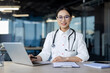 © Liubomir - Professional and friendly female doctor wearing glasses and a stethoscope using a laptop in a contemporary office setting. Her confident smile suggests a high level of expertise and approachability.