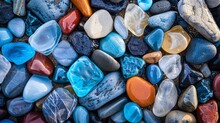 Detailed Aerial View Of A Collection Of Polished Stones And Bright Blue Sea Glass On A Beach, Highlighting Natural Textures And Colors