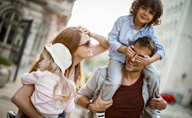 Wall Mural - Joyful family with young child shopping and walking in the city