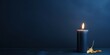 Navy Blue background with white thin wax candle with a small lit flame for funeral grief death dead sad emotion with copy space texture for display 