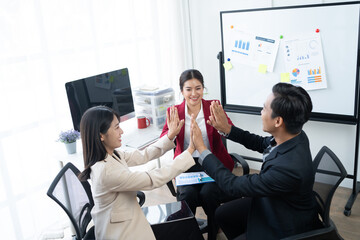 Wall Mural - Group of young business people discussing business while working by using line chart  and laptop in the office together 