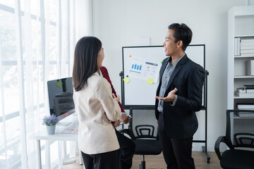 Wall Mural - Group of young business people discussing business while working by using line chart  and laptop in the office together 